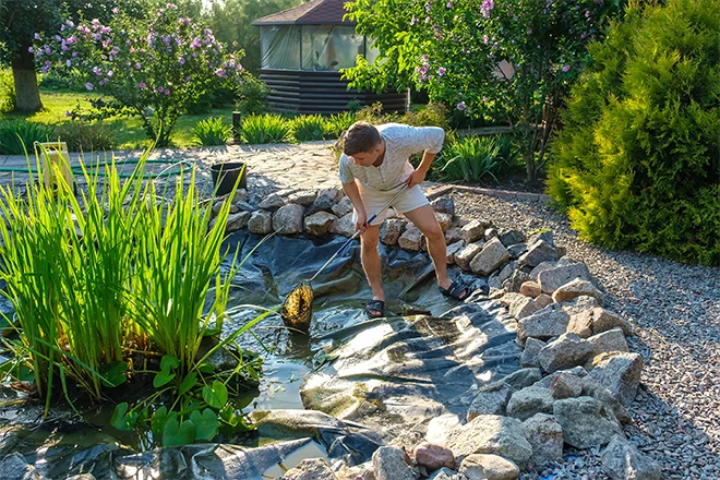 A guy performing pond maintenance A guy performing pond maintenance