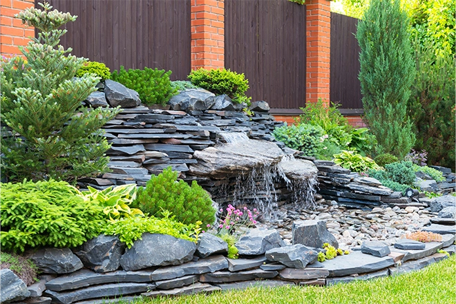 Pondless waterfall with a bunch of flat rocks in a garden Pondless waterfall with a bunch of flat rocks in a garden